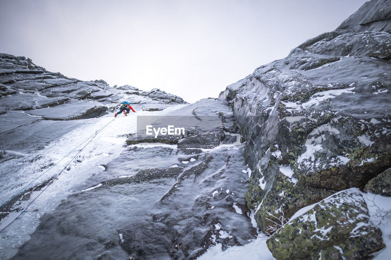 An alpine ice climber climbing a steep section on a large mountain