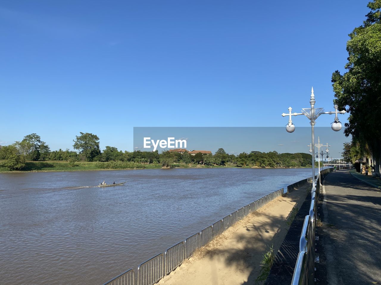 water, sky, nature, tree, plant, blue, river, shore, clear sky, no people, reflection, day, sunny, body of water, tranquility, transportation, travel, environment, sunlight, land, coast, travel destinations, beauty in nature, outdoors, scenics - nature, beach, road, landscape, architecture, waterway, reservoir, tranquil scene, street, tourism, city, vacation, trip, holiday, walkway, summer