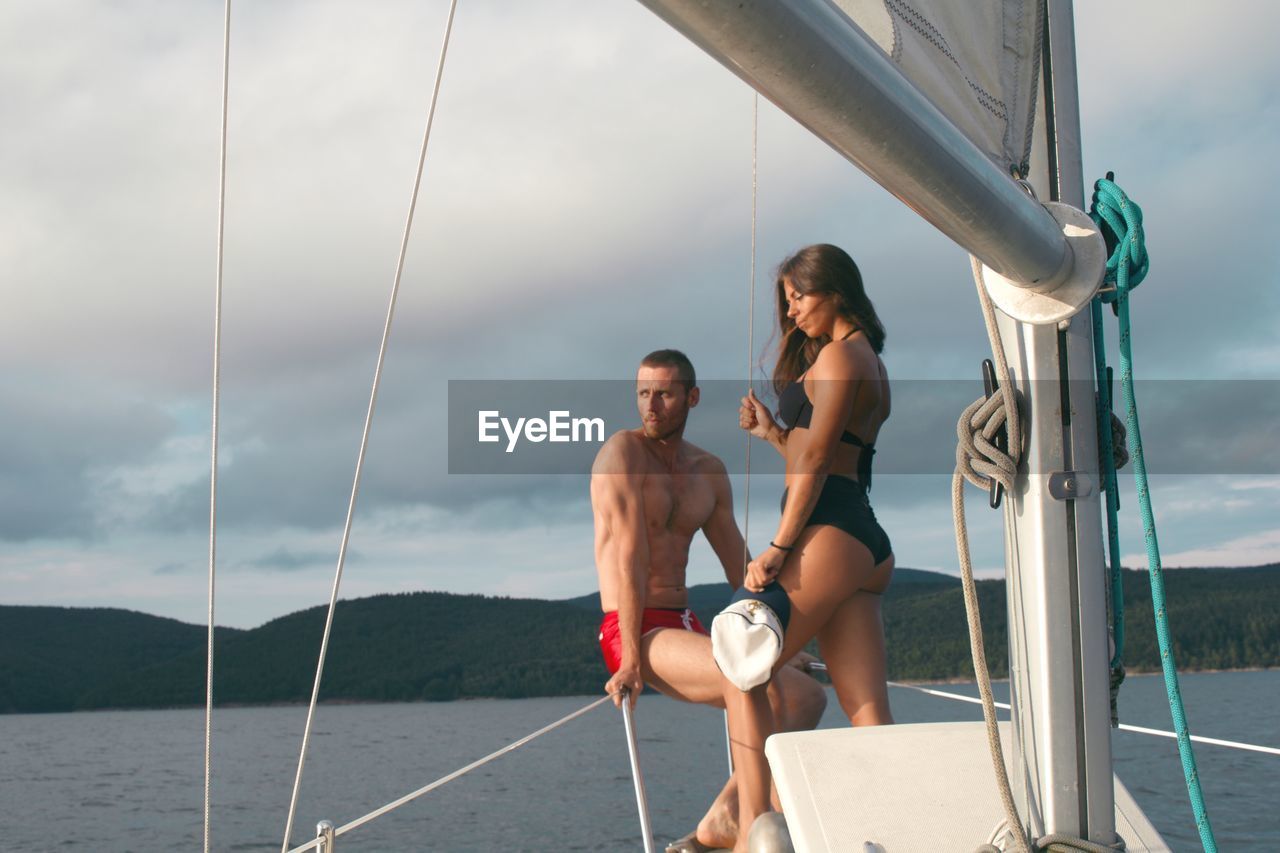 Young couple on yacht against sky