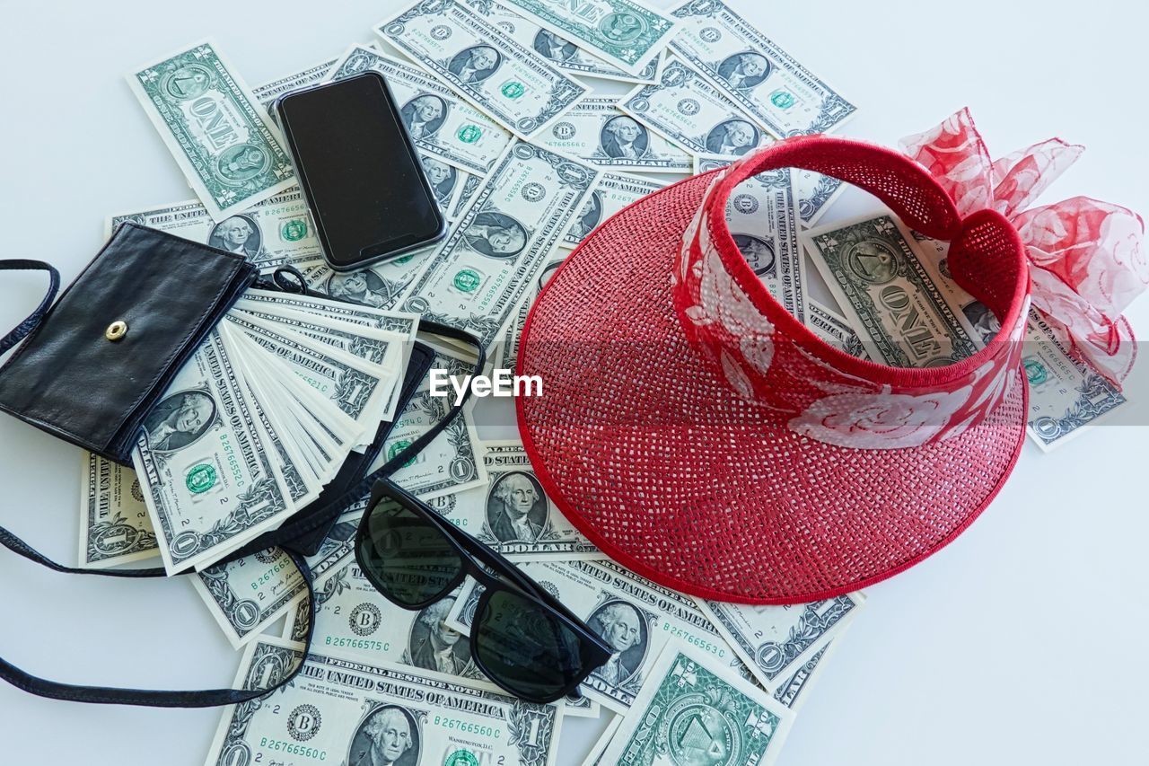 High angle view of personal accessories over paper currency on table