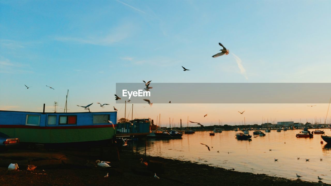 Harbor by lake against sky during sunset