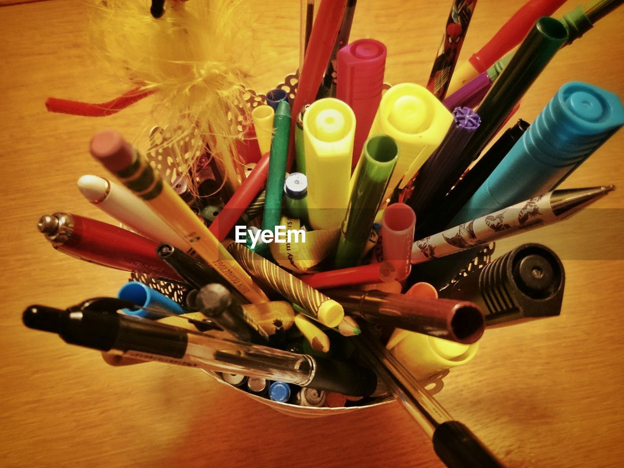 High angle view of pens and pencils in holder on wooden table