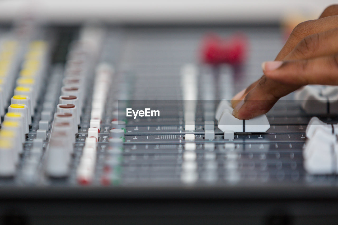 hand, technology, mixing console, sound mixer, audio equipment, selective focus, one person, sound recording equipment, adult, music, control, close-up, occupation, indoors, studio, arts culture and entertainment, recording studio, control panel, industry, technician, equipment, mixing, working, business finance and industry, finger, adjusting, men, skill, pushing, business