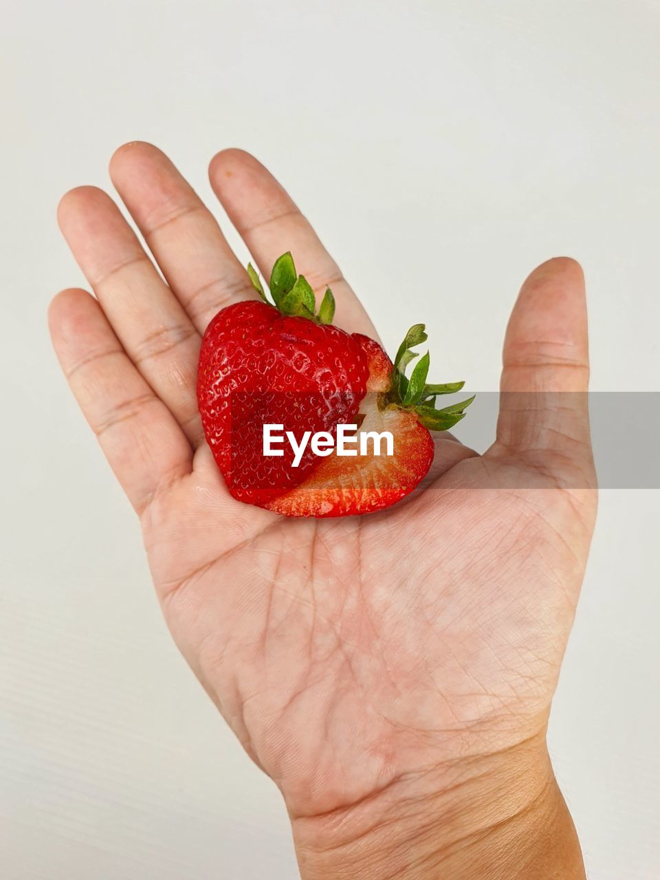 CLOSE-UP OF HAND HOLDING STRAWBERRY