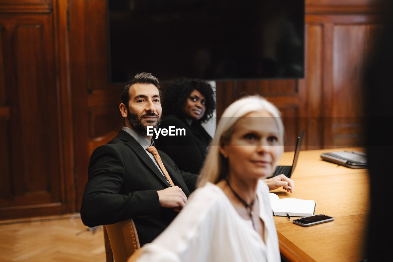 Multiracial colleagues sitting at conference table in board room during meeting