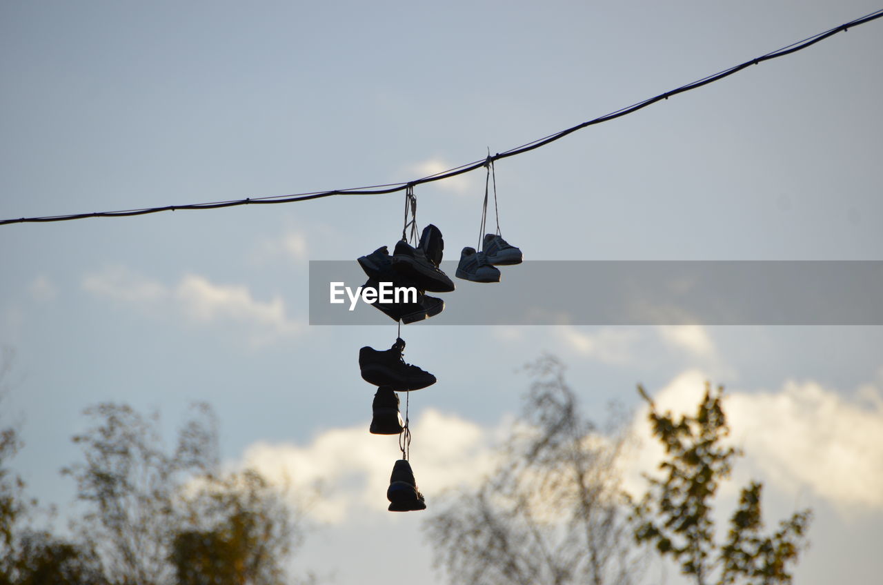 Low angle view of shoes hanging on tree against sky