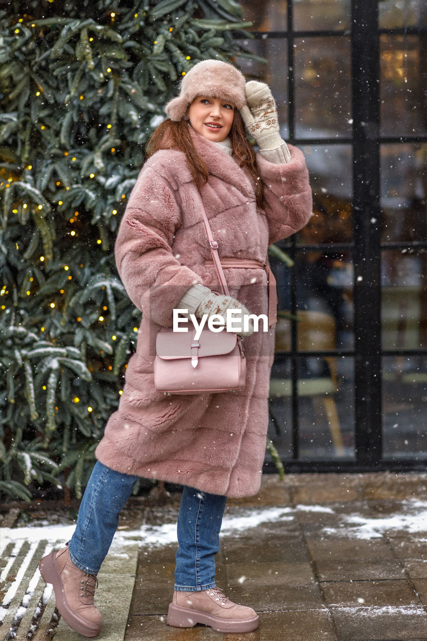 portrait of young woman wearing warm clothing standing in city