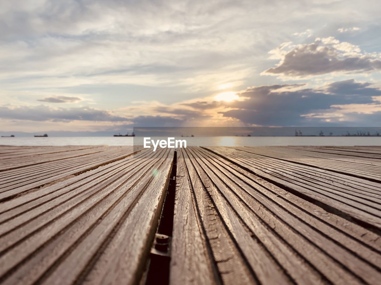 Surface level of boardwalk on pier against sky