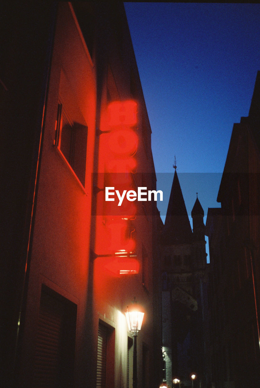 LOW ANGLE VIEW OF ILLUMINATED BUILDINGS AGAINST SKY AT NIGHT