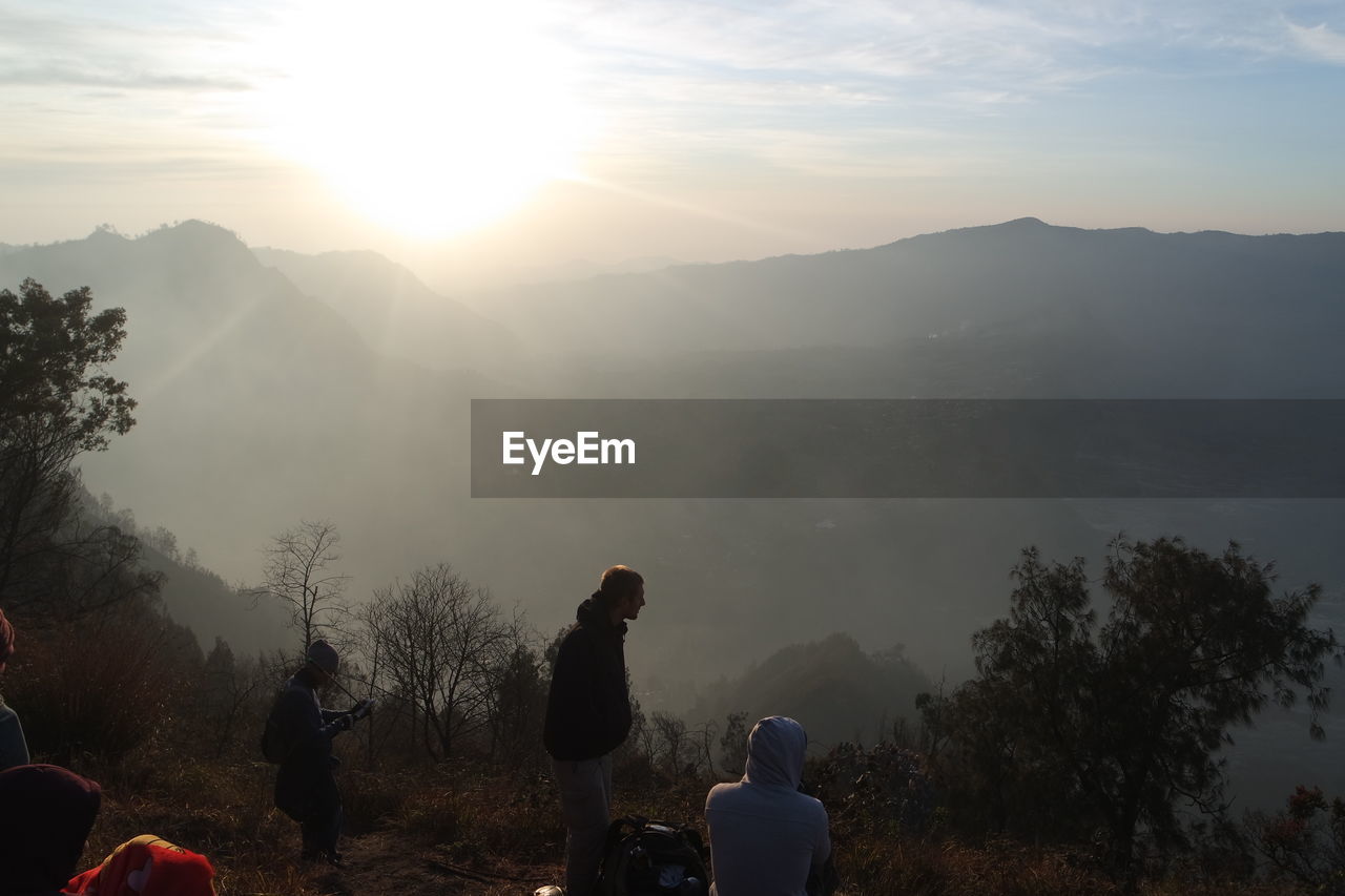 People on mountain against sky during sunrise