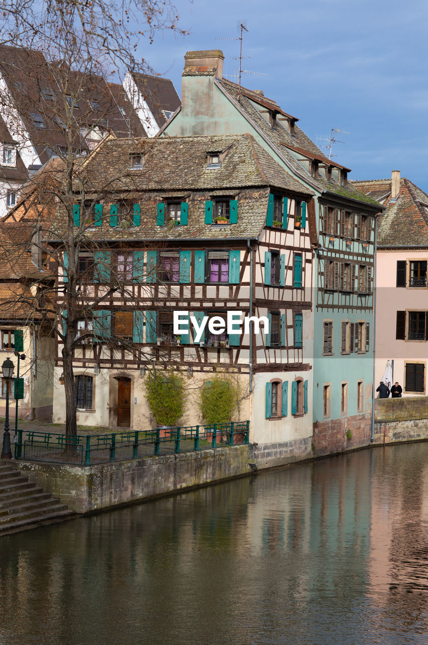 Buildings by canal against sky