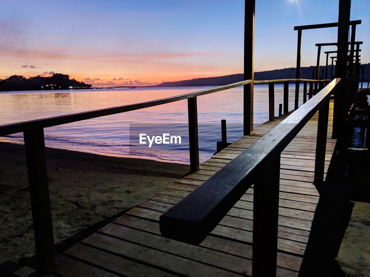 PIER BY LAKE AGAINST SKY DURING SUNSET