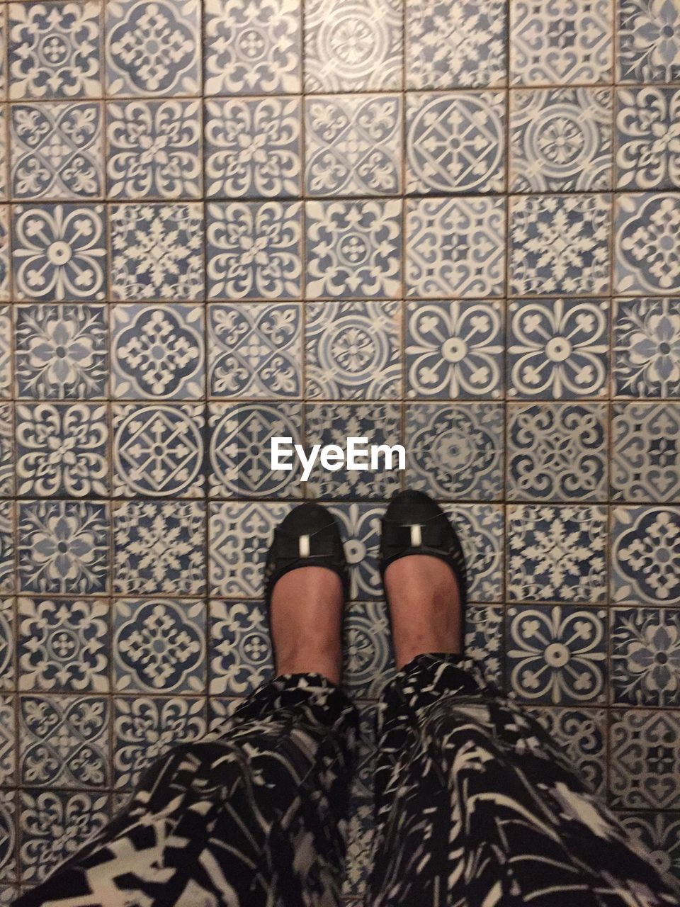 LOW SECTION OF WOMAN WALKING ON TILED FLOOR