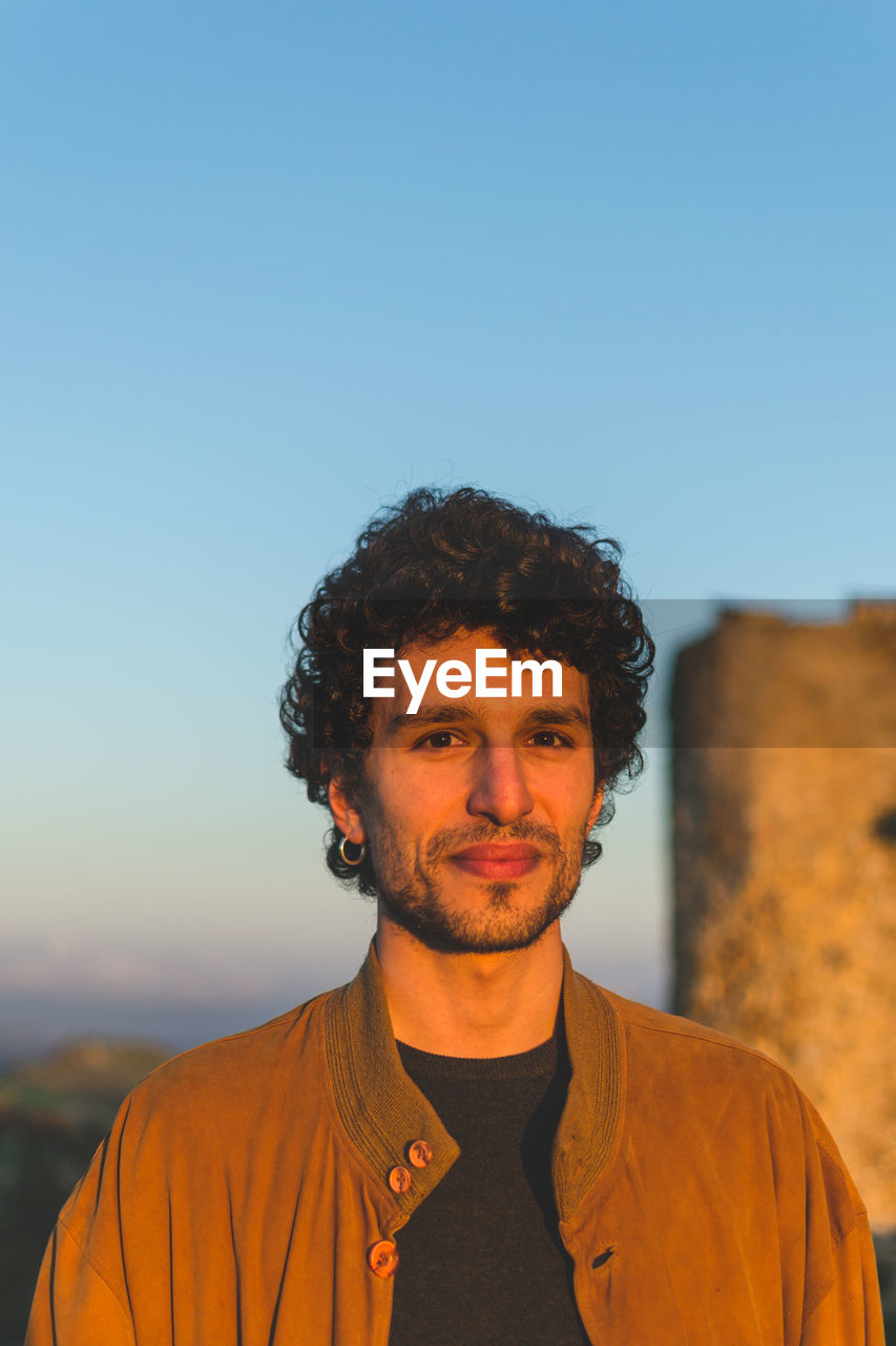 Portrait of smiling man standing against clear sky