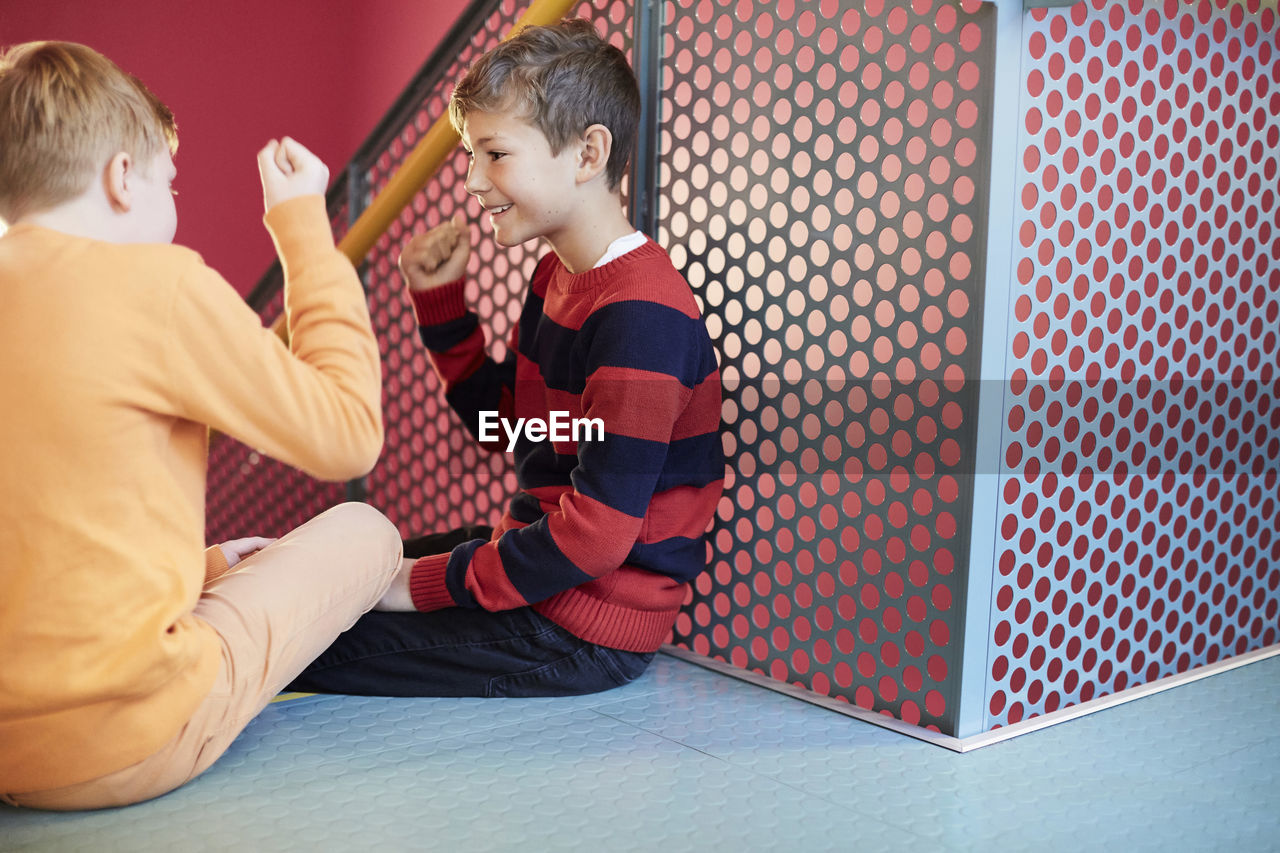 Middle school boys playing rock-paper-scissors on staircase