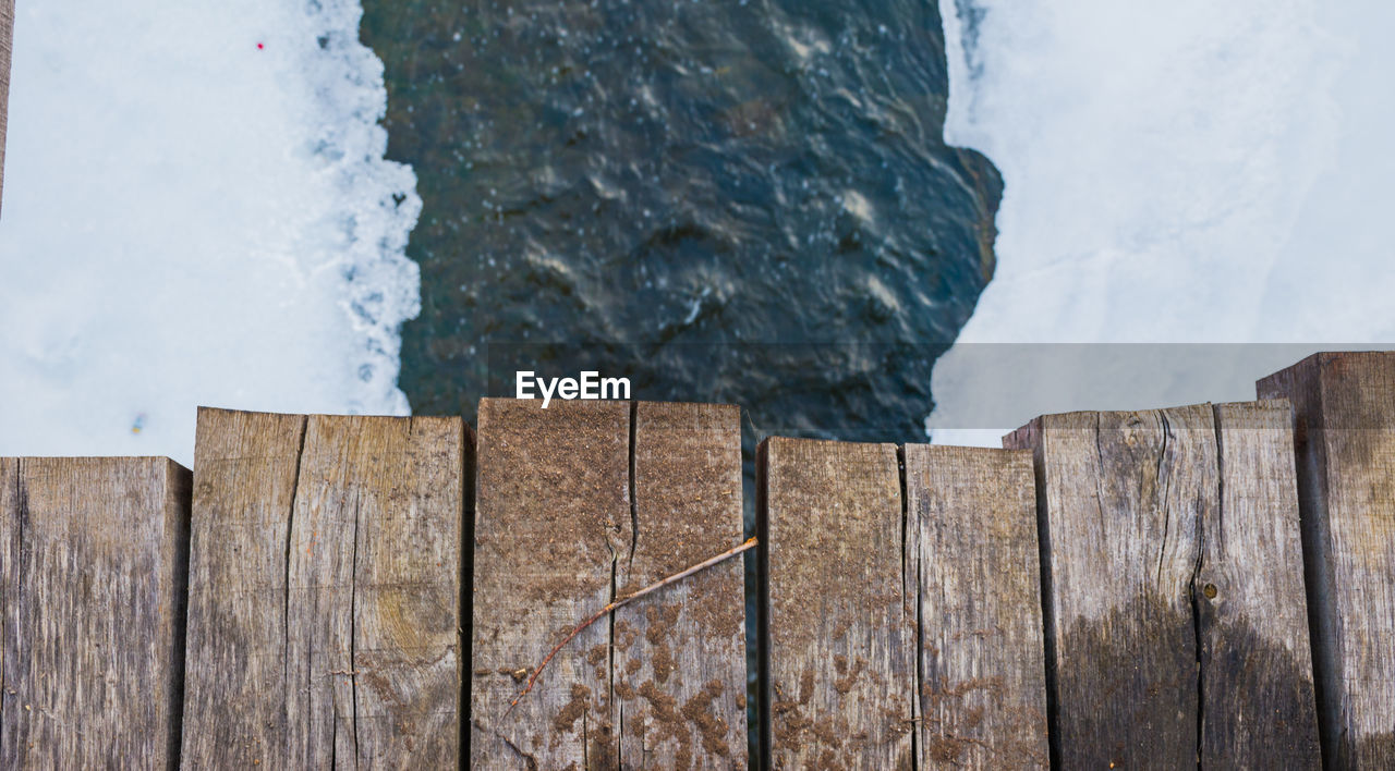 CLOSE-UP OF LIZARD ON WOOD BY WATER AGAINST SKY