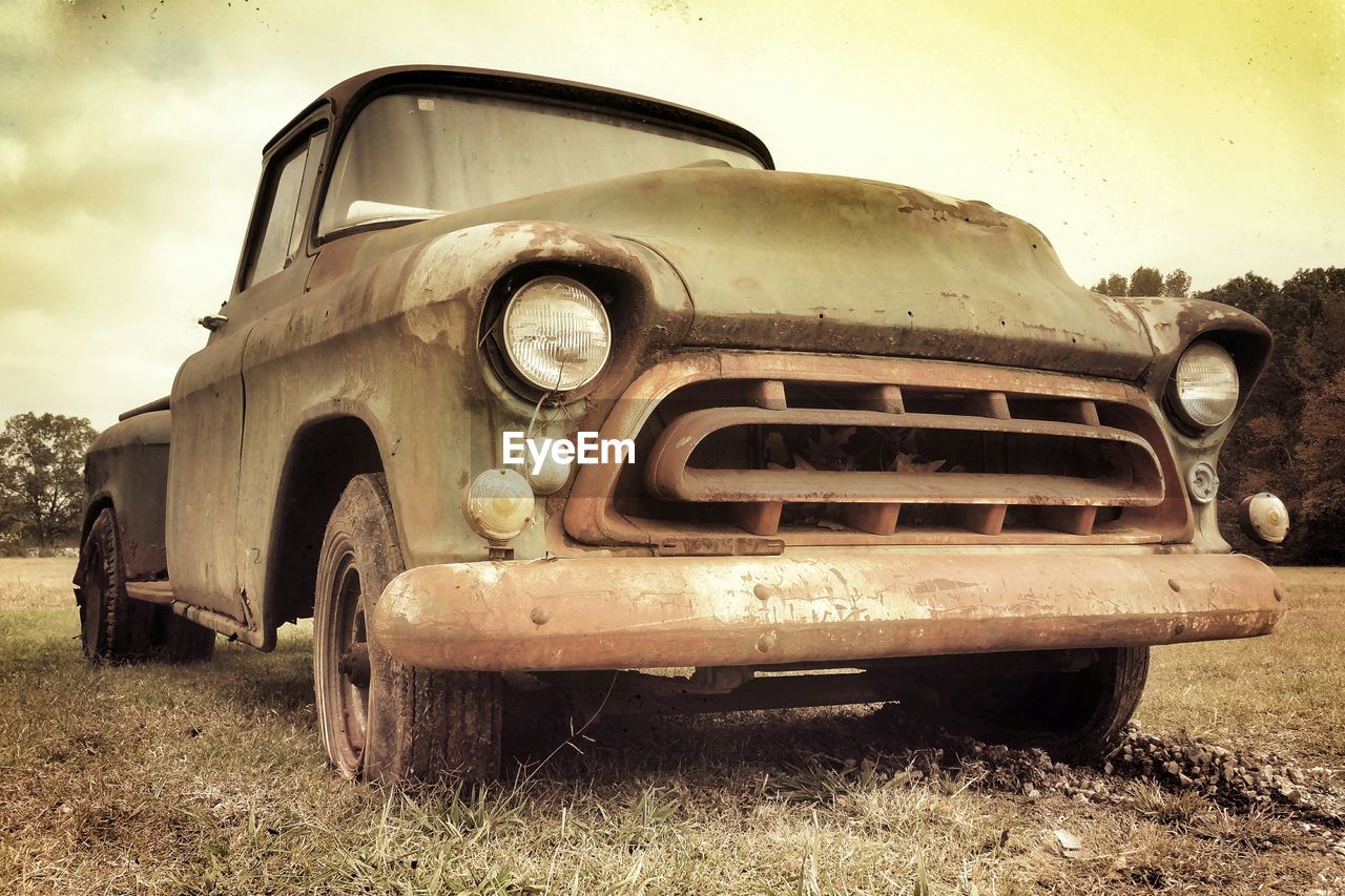 Low angle view of rusty abandoned car on field