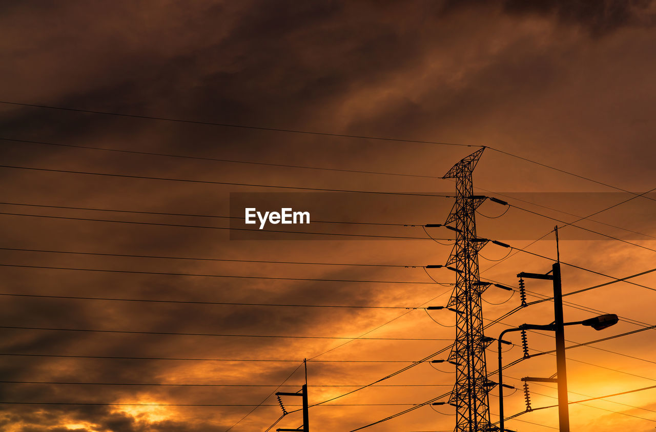 Silhouette high voltage electric pylon and electrical wire with an orange sky. electricity poles.