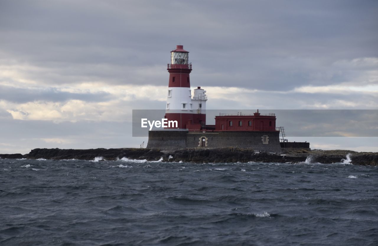 Lighthouse by sea against sky