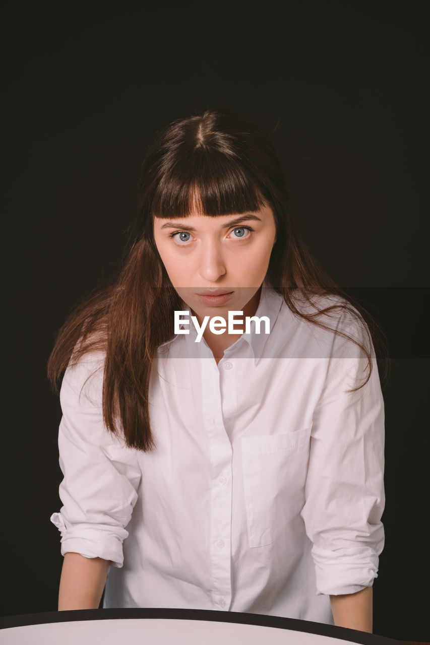 PORTRAIT OF BEAUTIFUL YOUNG WOMAN AGAINST BLACK BACKGROUND