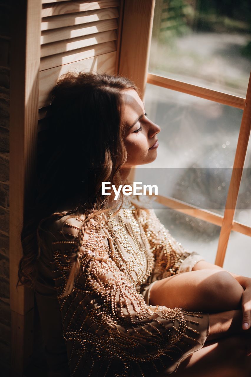 Woman sitting by window at home