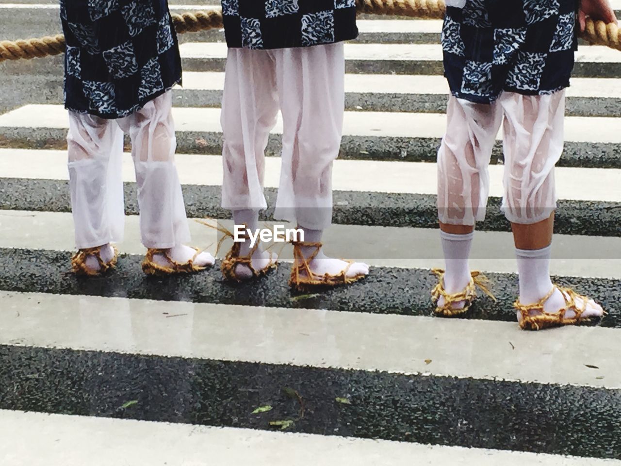 Low section of people standing on zebra crossing during rainy season