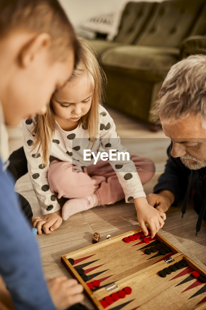 Girl learning backgammon with grandfather at home
