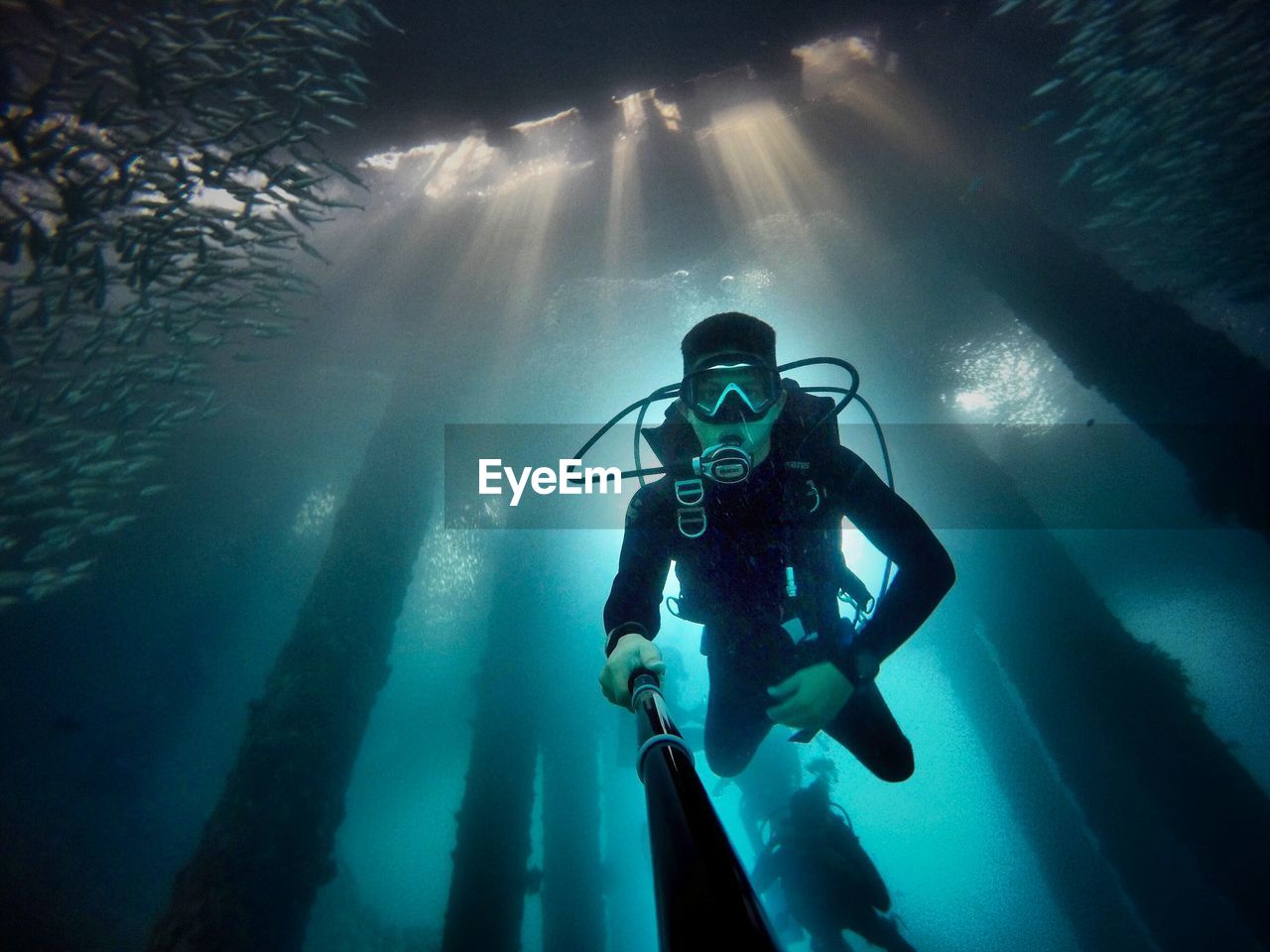 Portrait of young man with monopod while scuba diving in sea