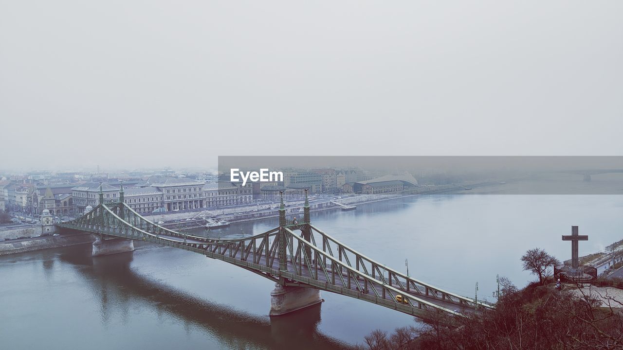 Bridge over river in city against sky