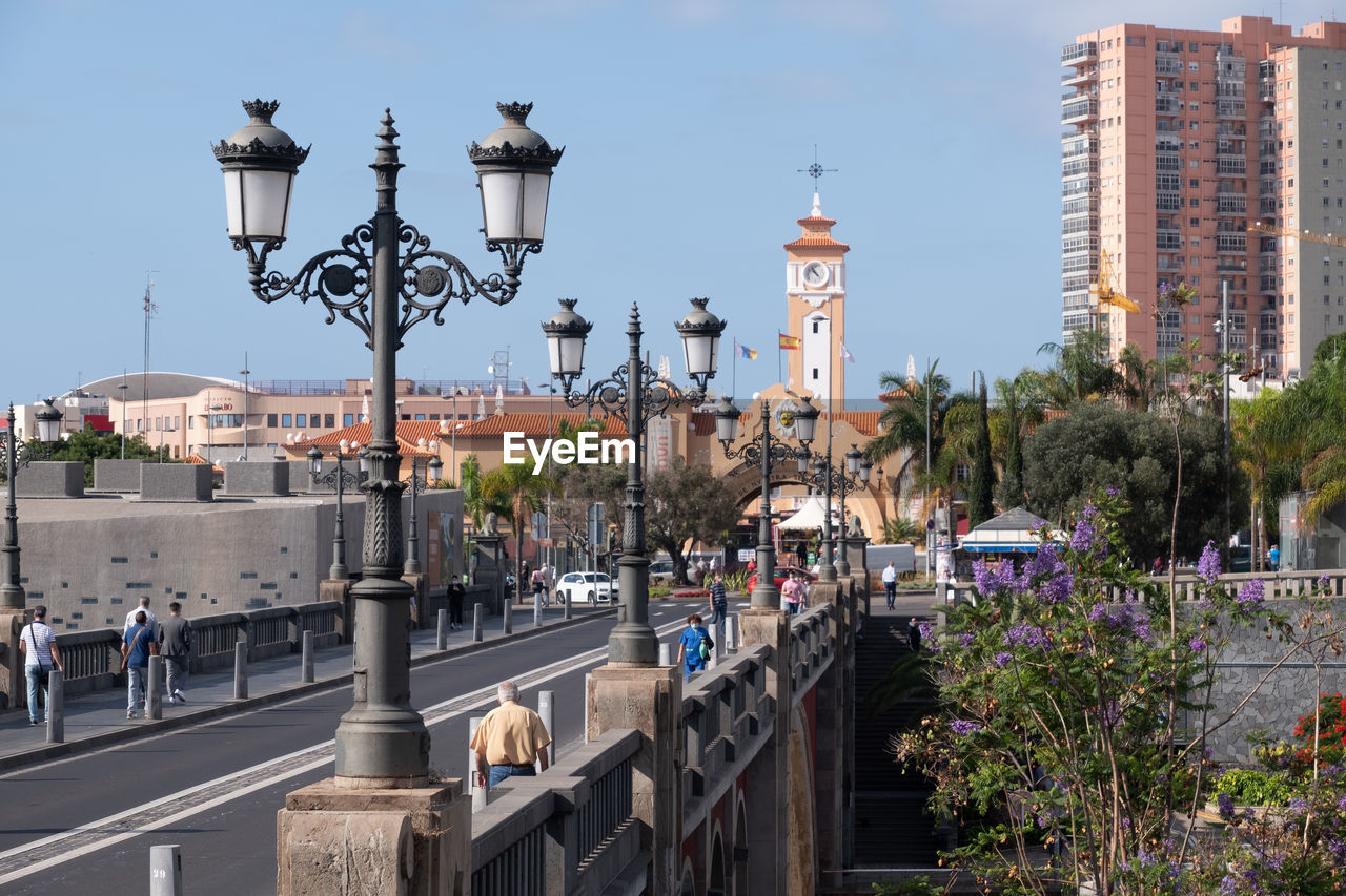 Bridge lined with historic lanterns and african market in the background on a sunny cloudless day.