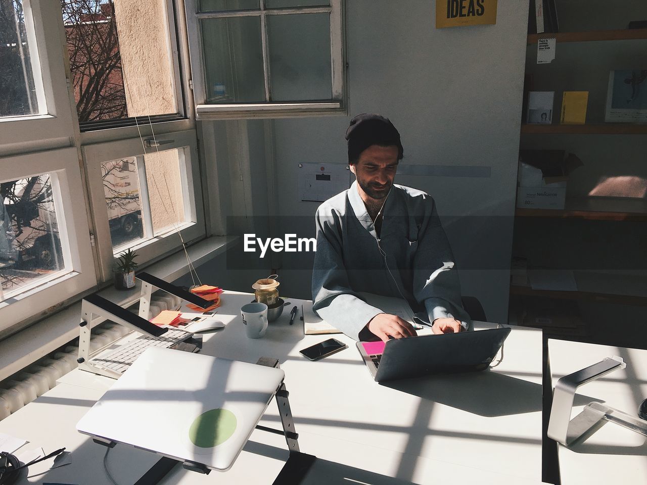 YOUNG MAN USING MOBILE PHONE IN OFFICE