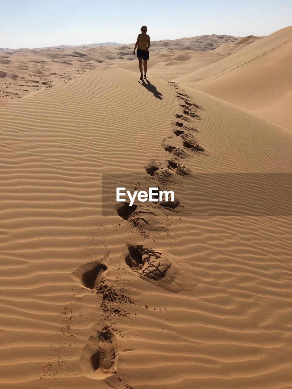 Woman walking on sand dune at desert