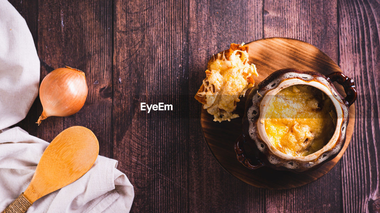 Homemade onion soup with cheese croutons in a pot on the table top view web banner