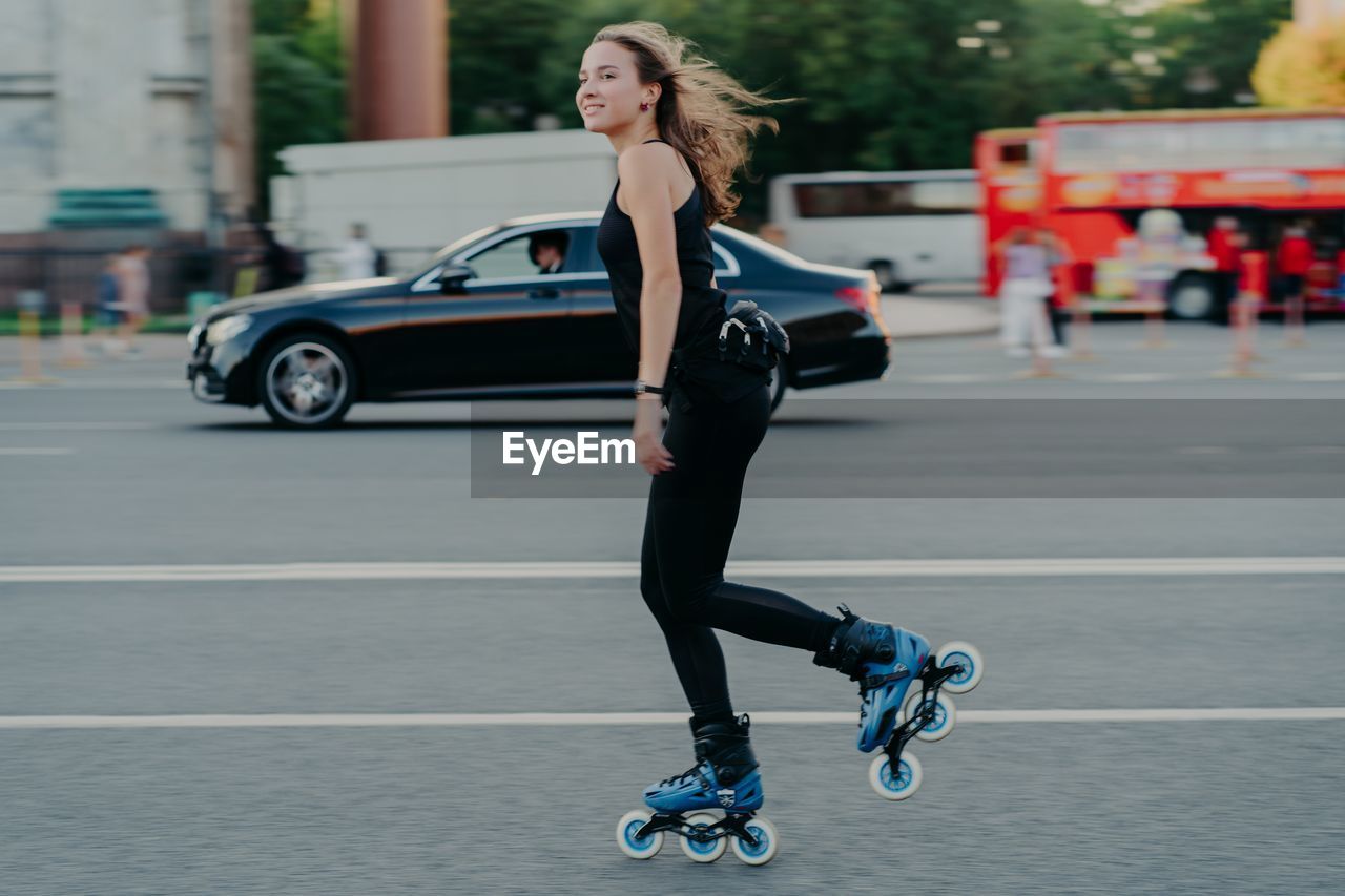 FULL LENGTH PORTRAIT OF YOUNG WOMAN IN CAR ON ROAD