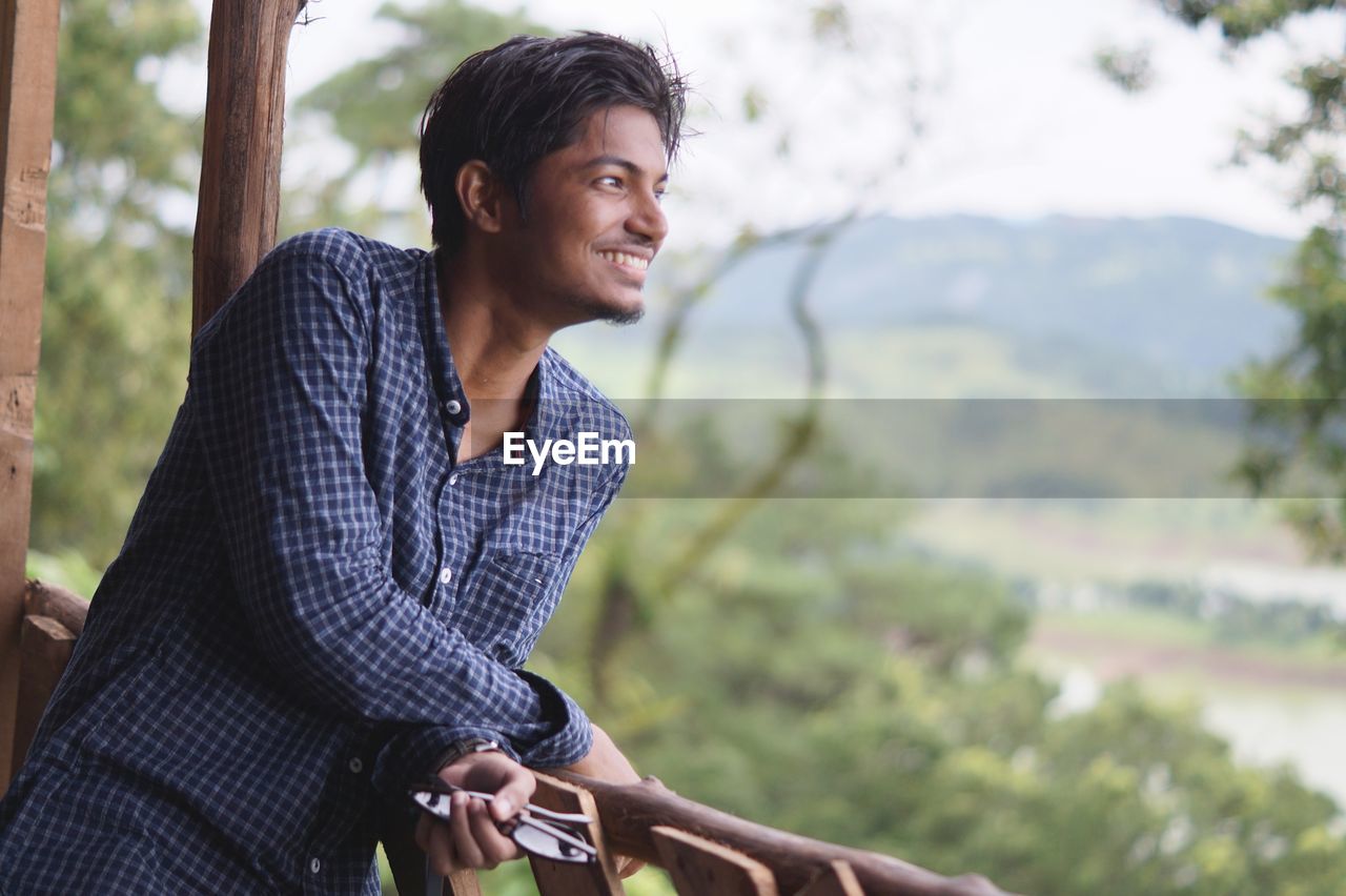 Smiling man standing by railing