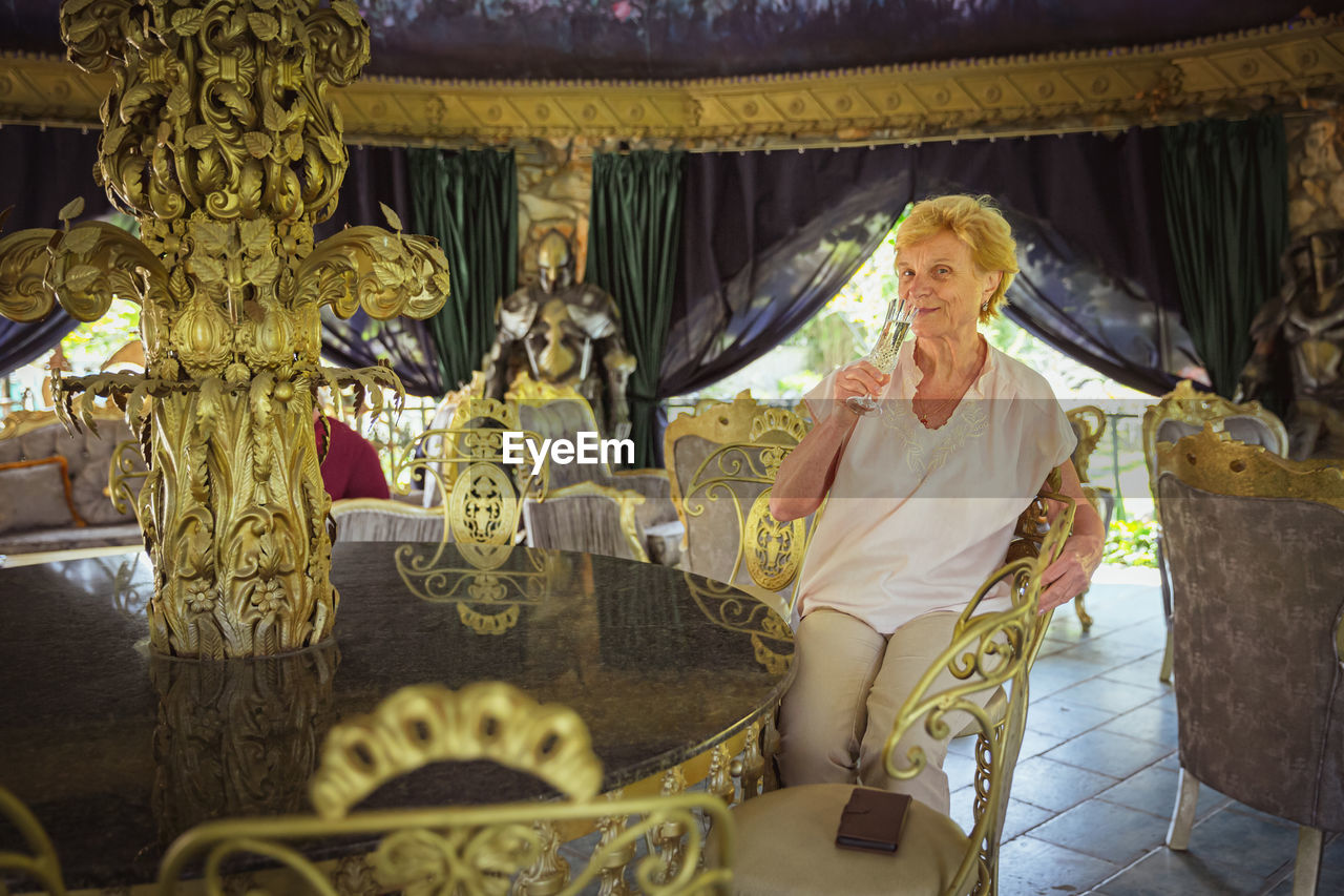 Elderly woman traveler sitting alone on the terrace of coffee shop