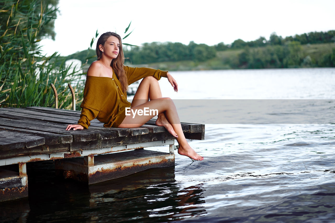 PORTRAIT OF YOUNG WOMAN SITTING IN LAKE