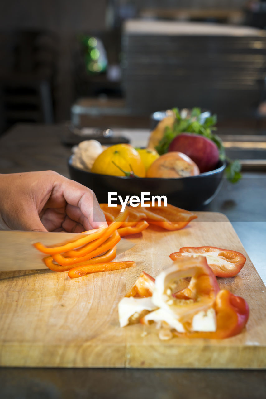 Cropped hands of man chopping red bell pepper on cutting board