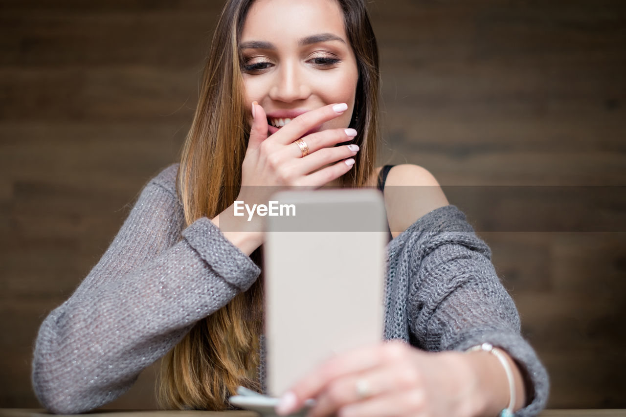 Smiling woman using phone at home