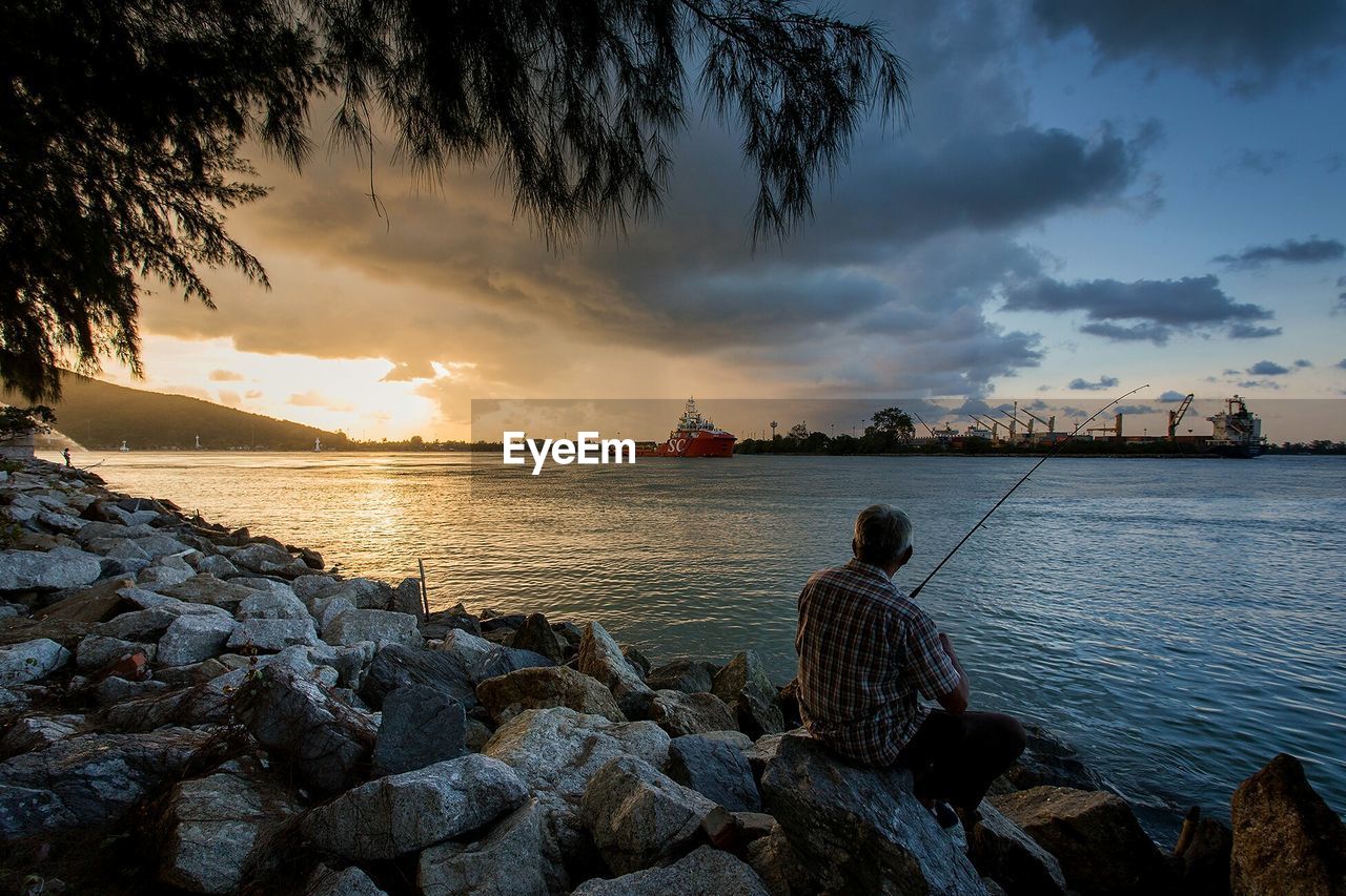 Rear view of man fishing at sea shore