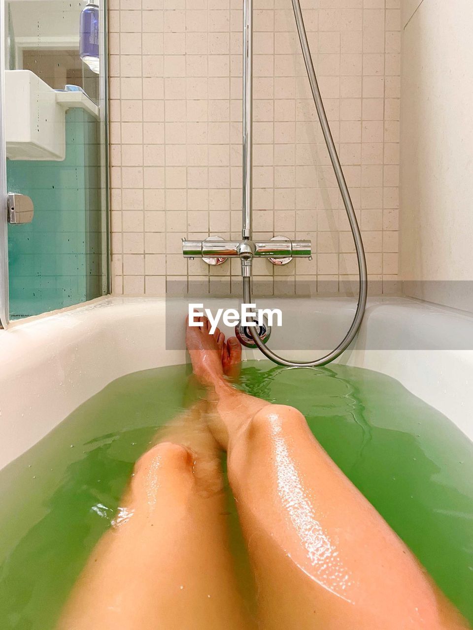Personal perspective view woman legs in bathtub with colorful salt