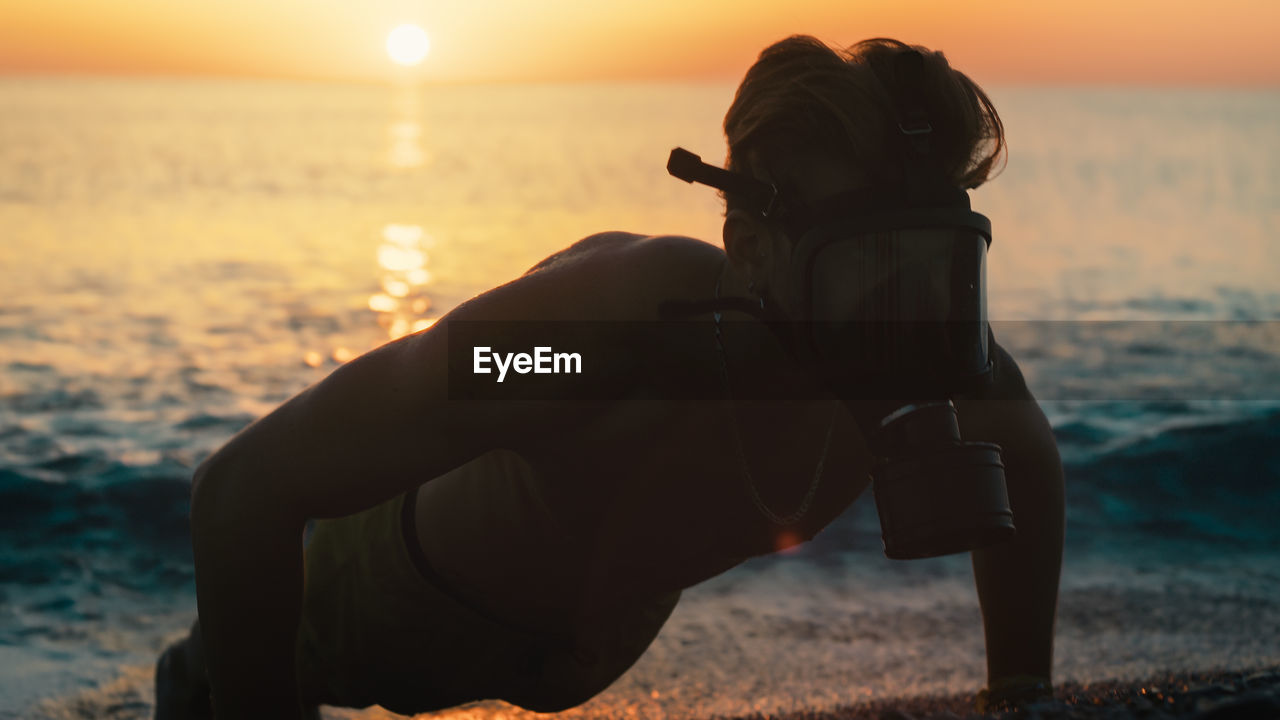 Man run at sunrise on the beach with gas mask