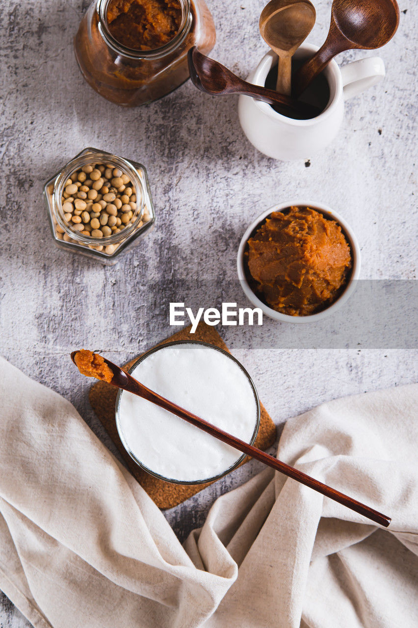 Miso-spiked latte in a glass and a bowl of miso paste on the table top and vertical view