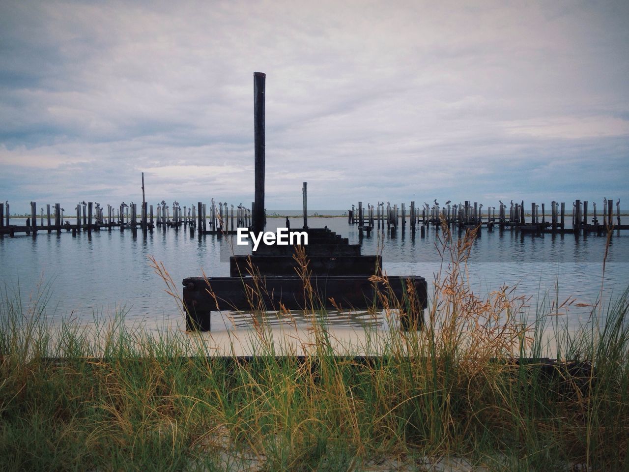 Wooden post on river against sky