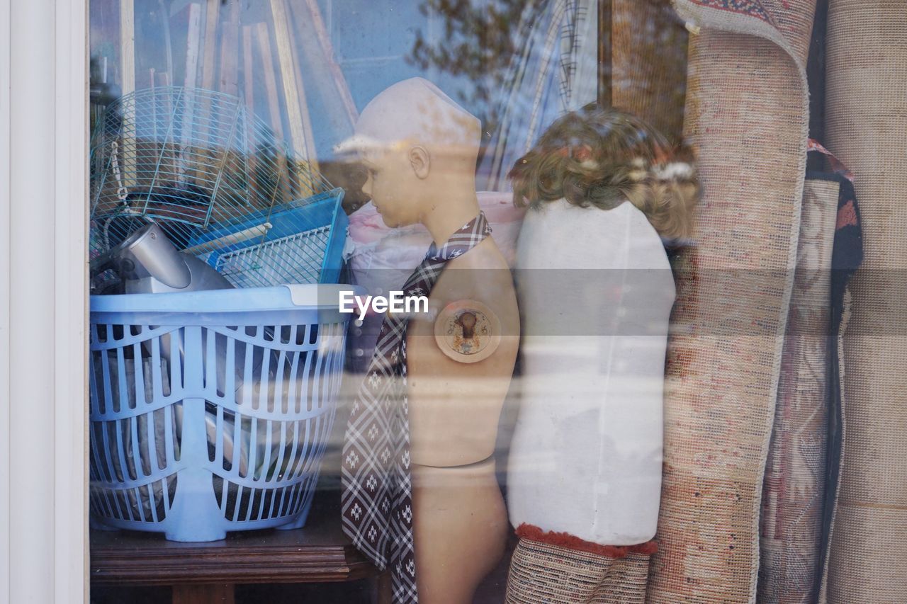 Mannequins and carpets seen through glass window of store