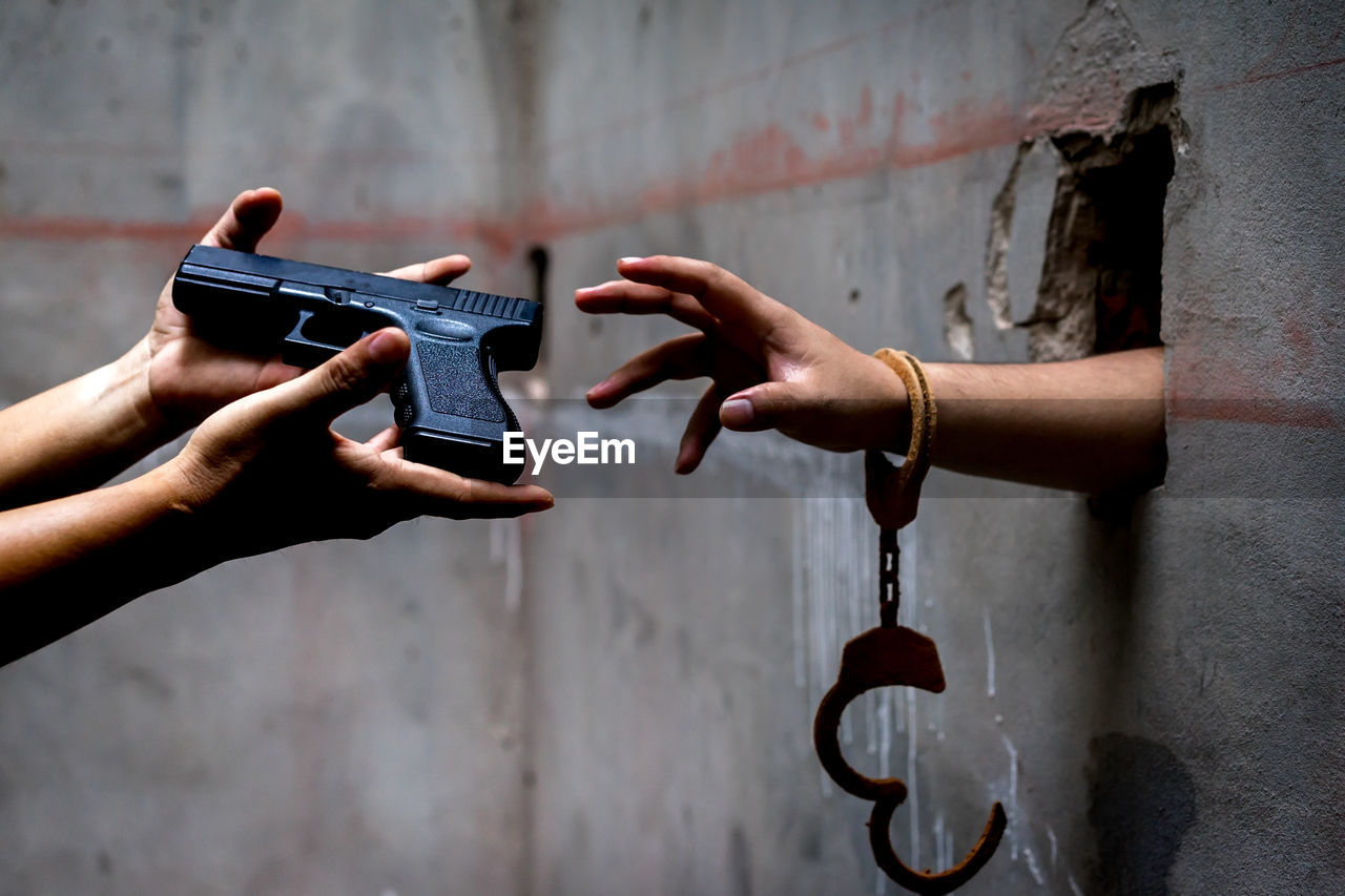 Cropped hand reaching handgun held by friend in prison