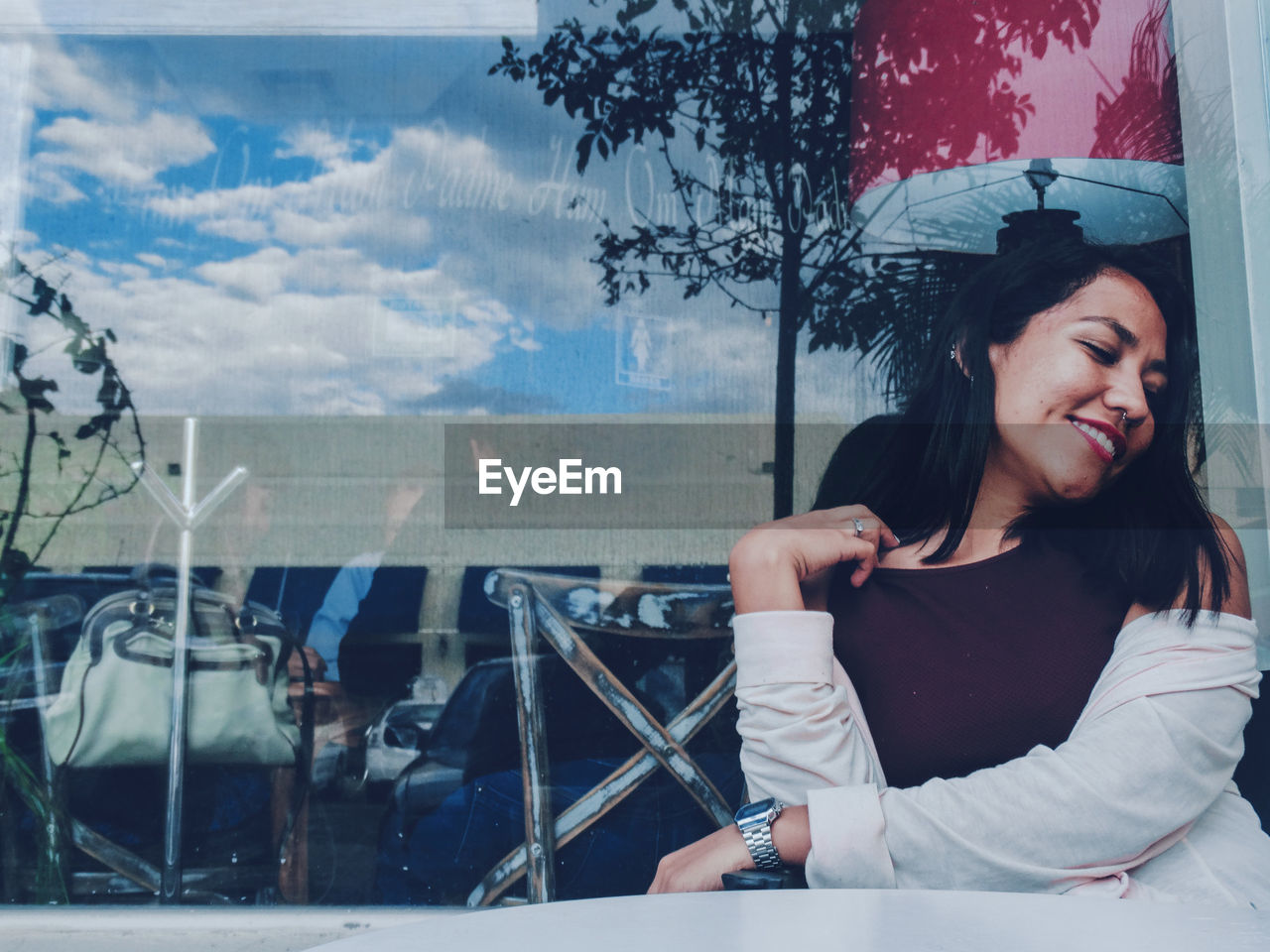 Smiling woman in restaurant seen through glass window