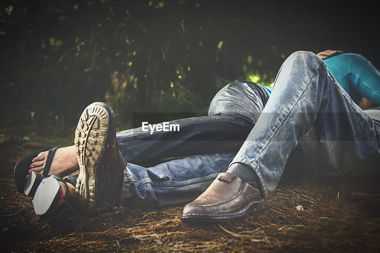 Low section of romantic couple lying on field
