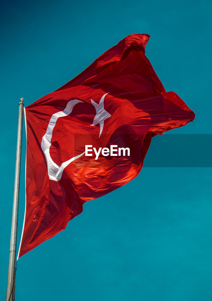 Low angle view of turkish flag against blue sky