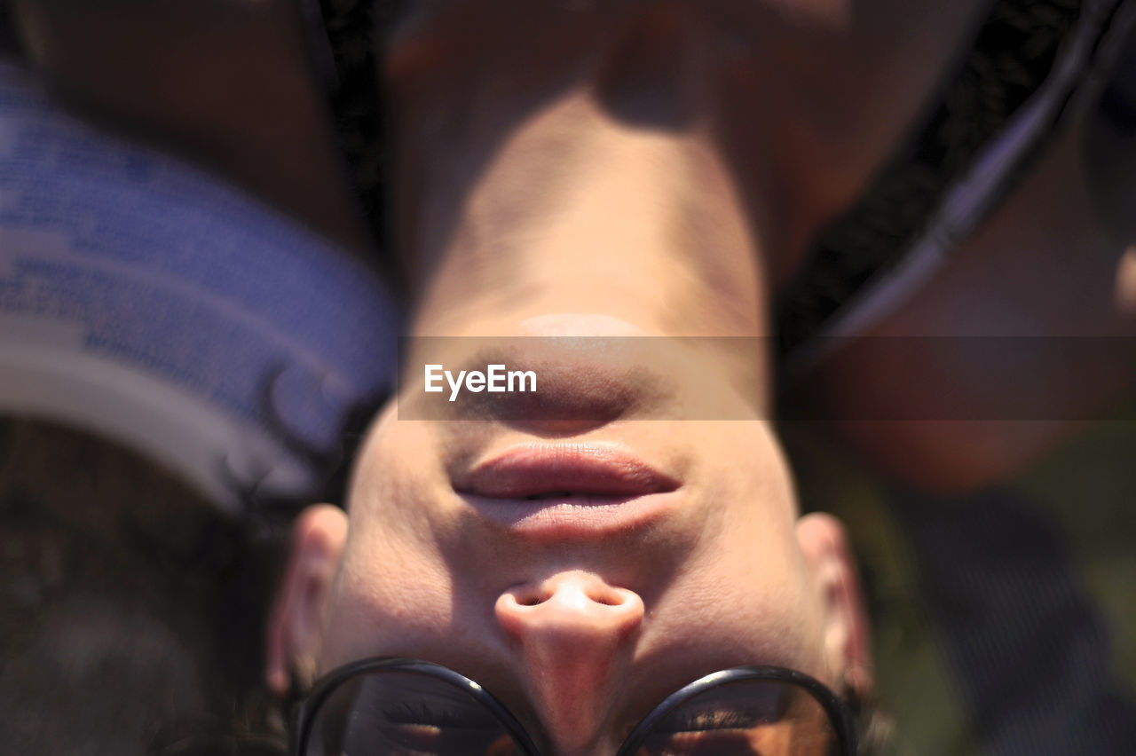 High angle close-up of young woman wearing sunglasses relaxing at beach